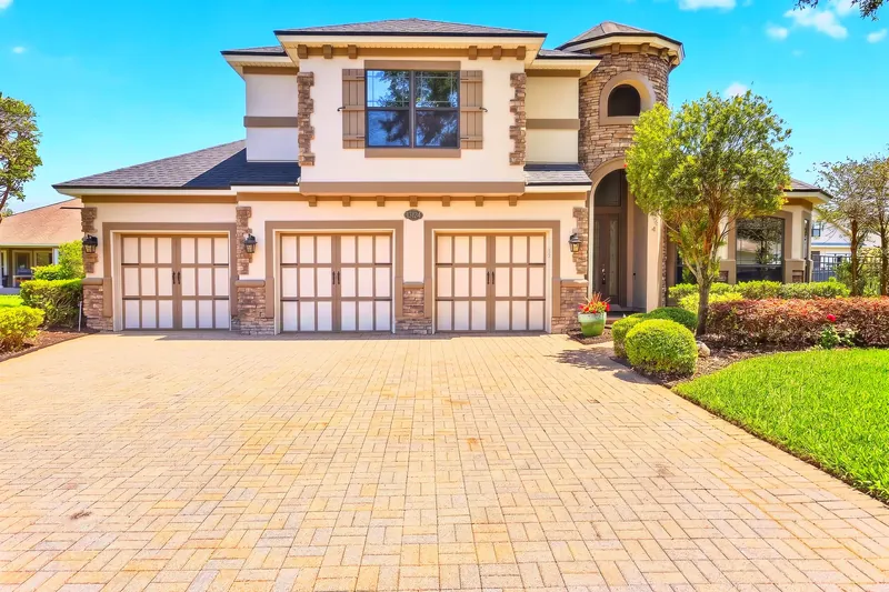 Two-story home with three-car garage and paver driveway